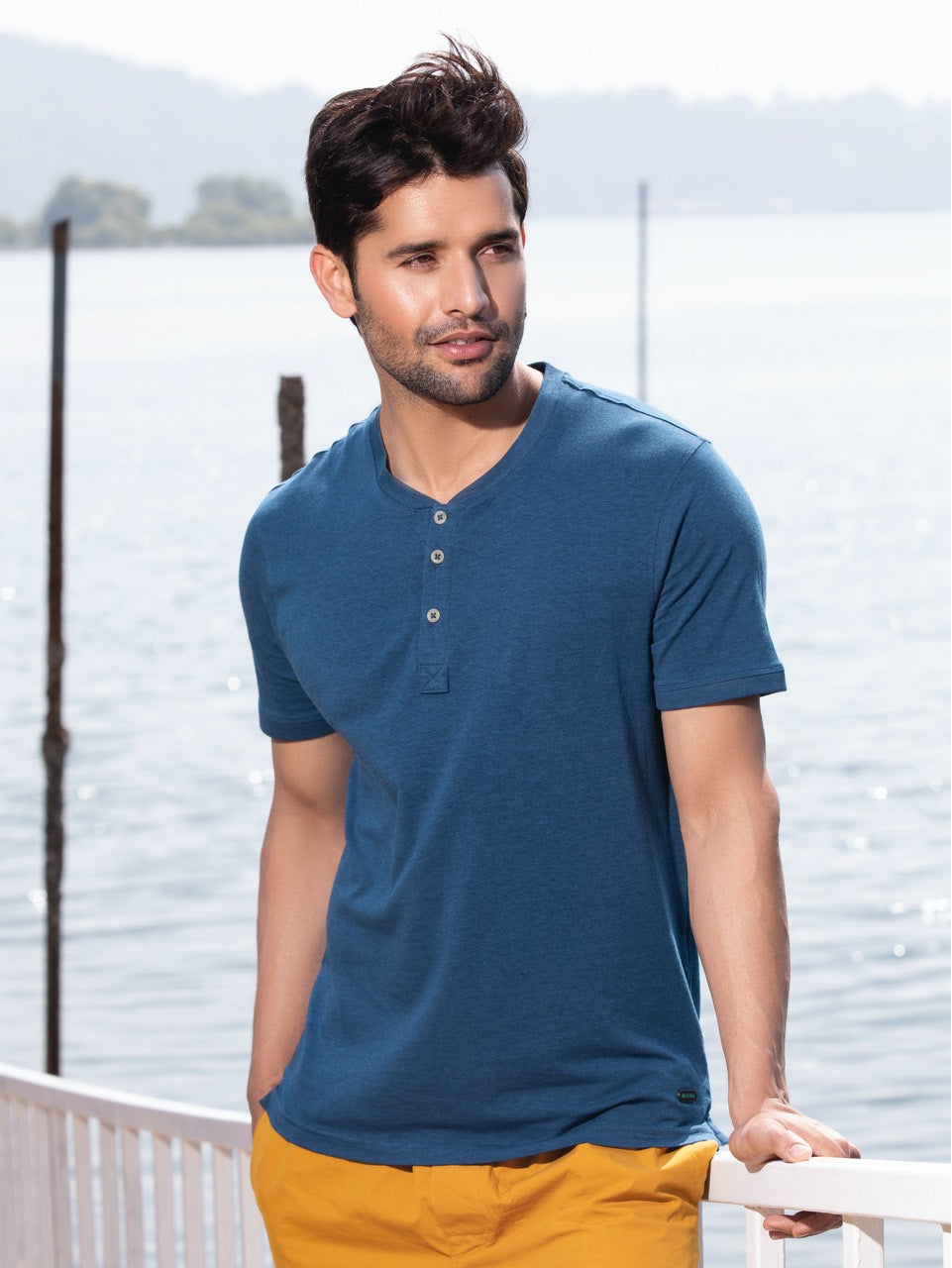 Man wearing a stylish henley shirt in a modern urban setting.